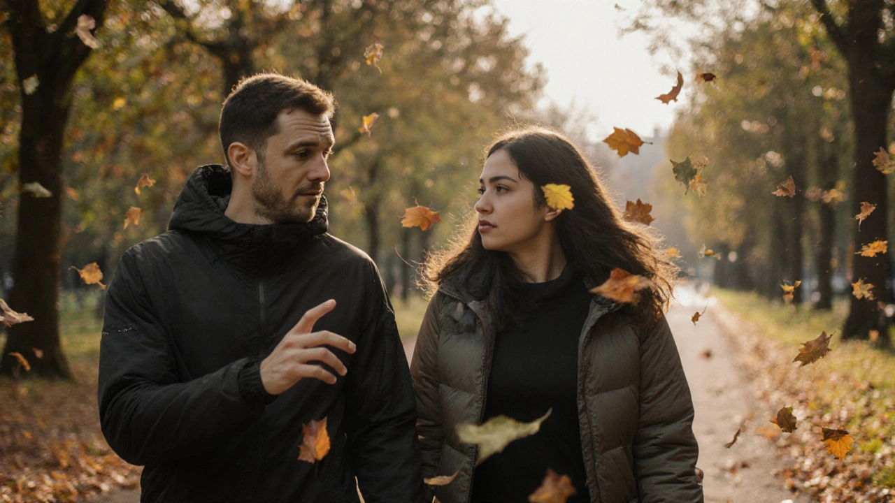 Two people walking through a park, one gesturing as the other listens.