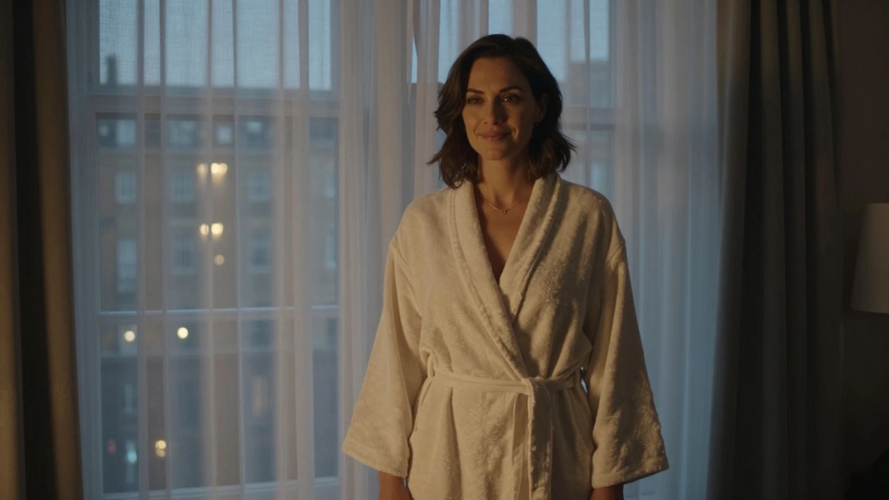 A woman in a robe standing by a window in natural twilight, radiating warmth and dignity.