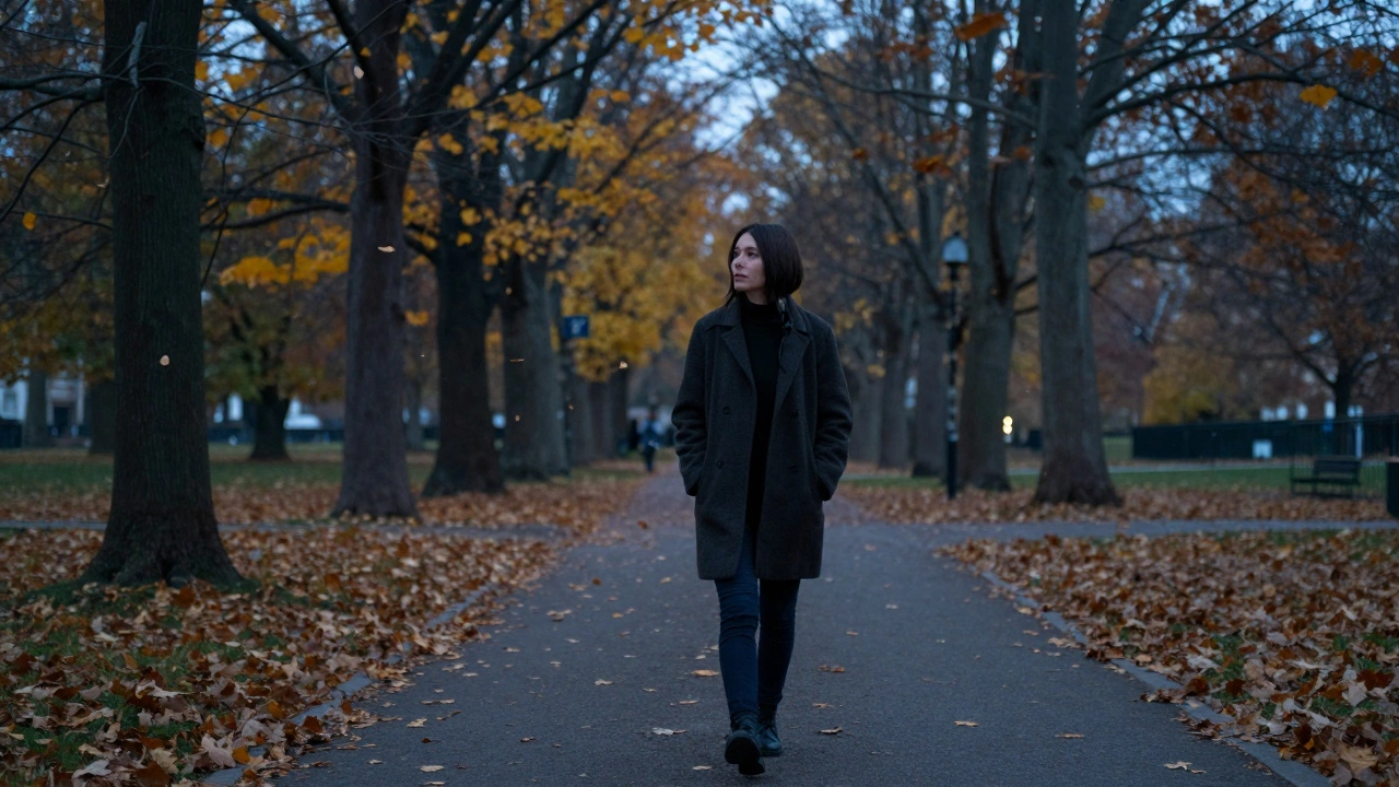 A person walking thoughtfully in a park at dusk, surrounded by falling leaves, serene and grounded.